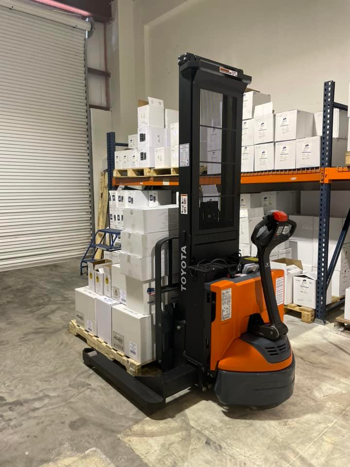 A toyota forklift is stacking boxes on a pallet in a warehouse.