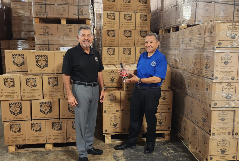 Two men are standing in front of a warehouse full of boxes