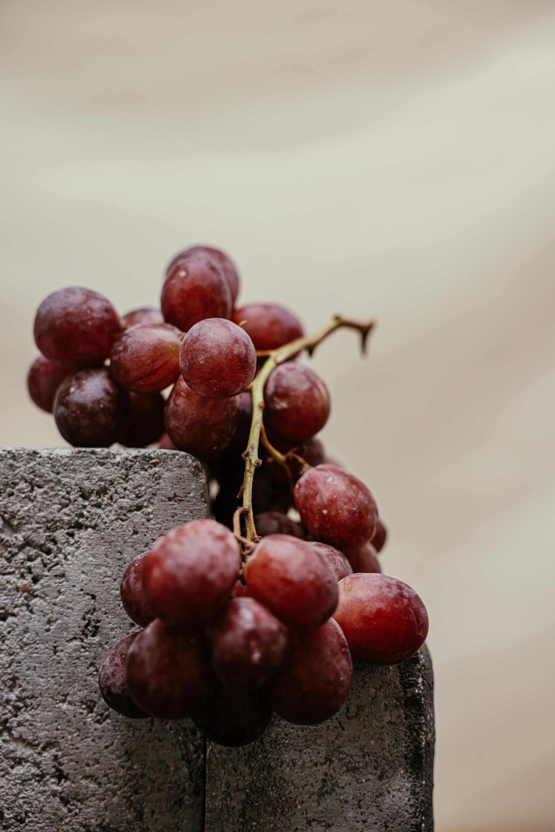 A bunch of red grapes sitting on top of a concrete block.