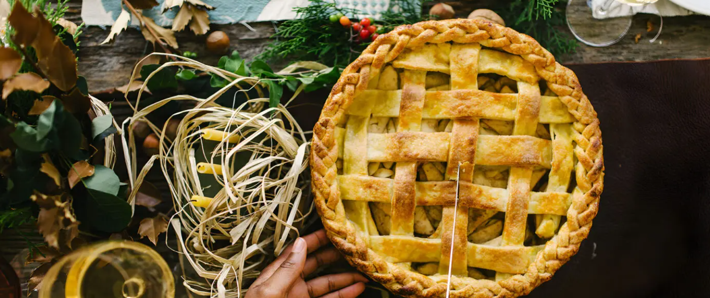 A person is holding a pie in their hands on a table.