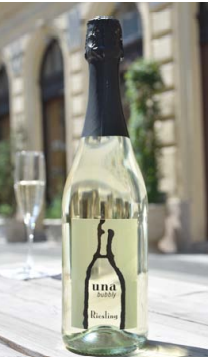 A bottle of una bubbly sits on a table next to a glass