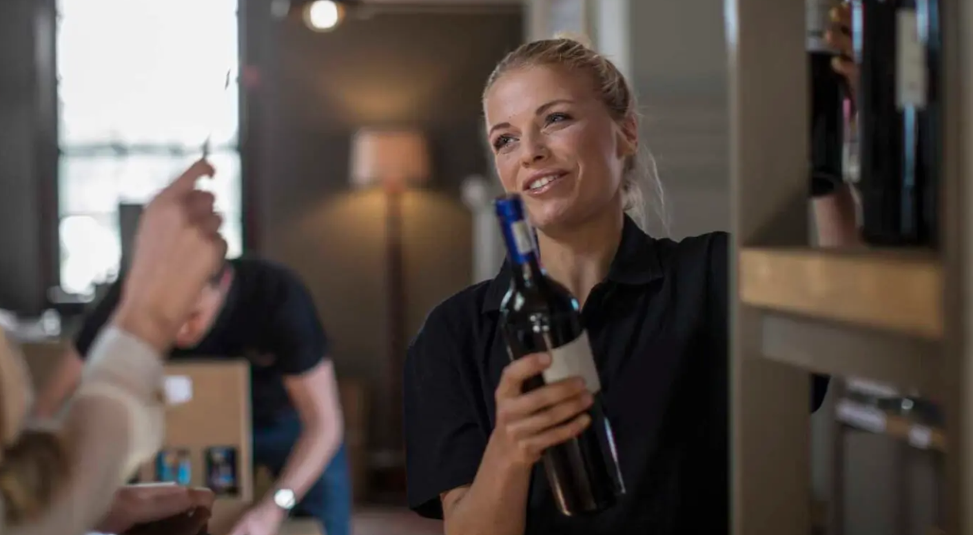 A woman is holding a bottle of wine in her hand.