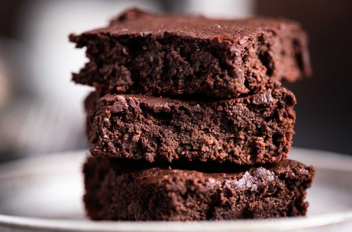Three brownies are stacked on top of each other on a white plate.
