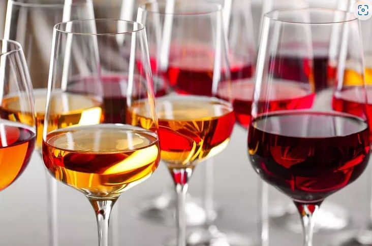 A row of wine glasses filled with different types of wine.