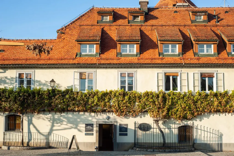 A white building with a red tiled roof and a fence around it.