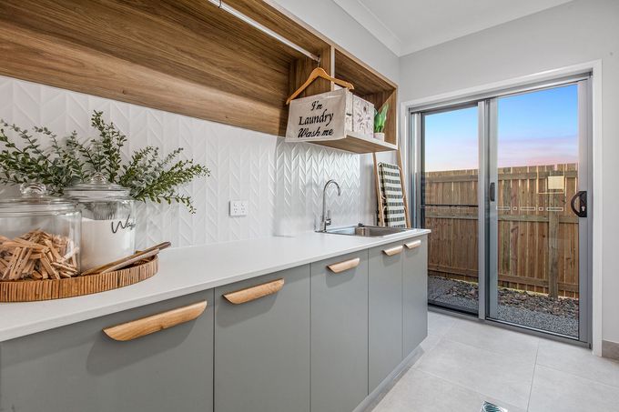 Custom laundry room cabinetry in sage green with timber handles and floating shelves, designed and built by cabinet makers in Mackay