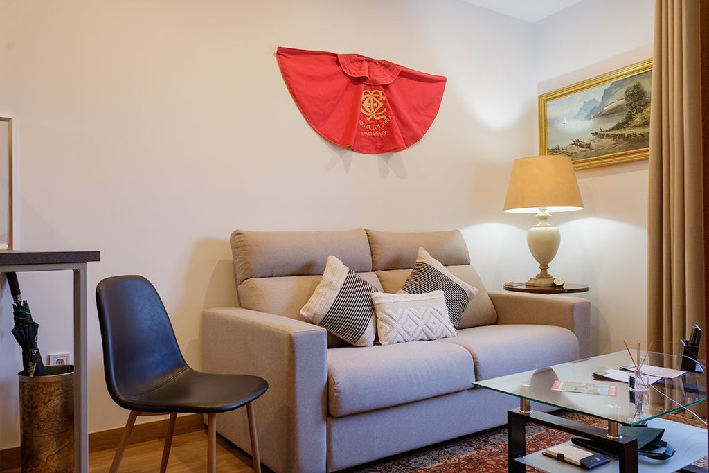 Acogedora sala de estar con un sofá beige, un sillón moderno, una decoración de pared roja y una pequeña mesa de café.