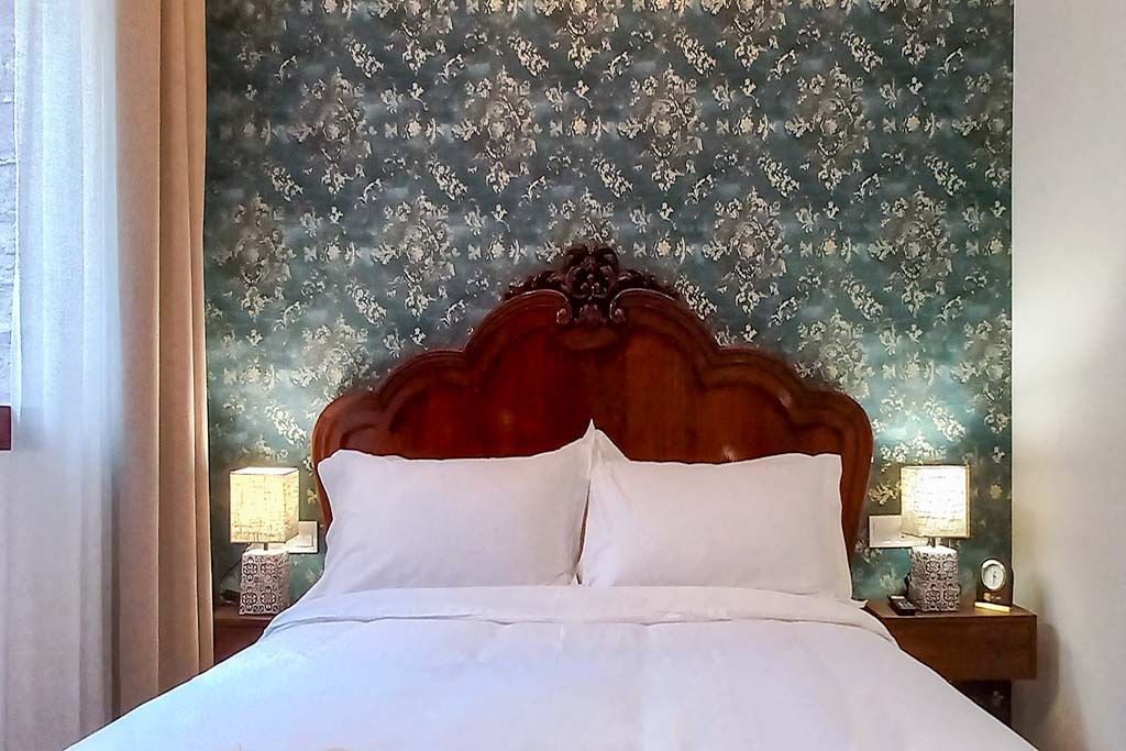 A bed with white sheets and pillows in a bedroom with a wooden headboard.