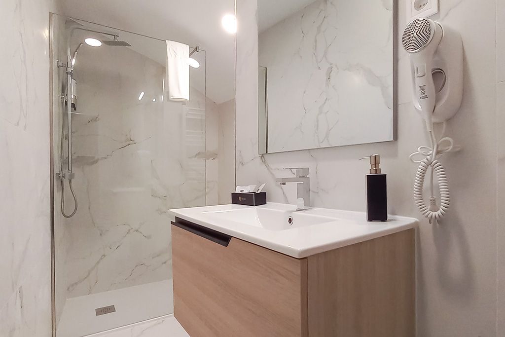 A bathroom with a sink , mirror and shower.