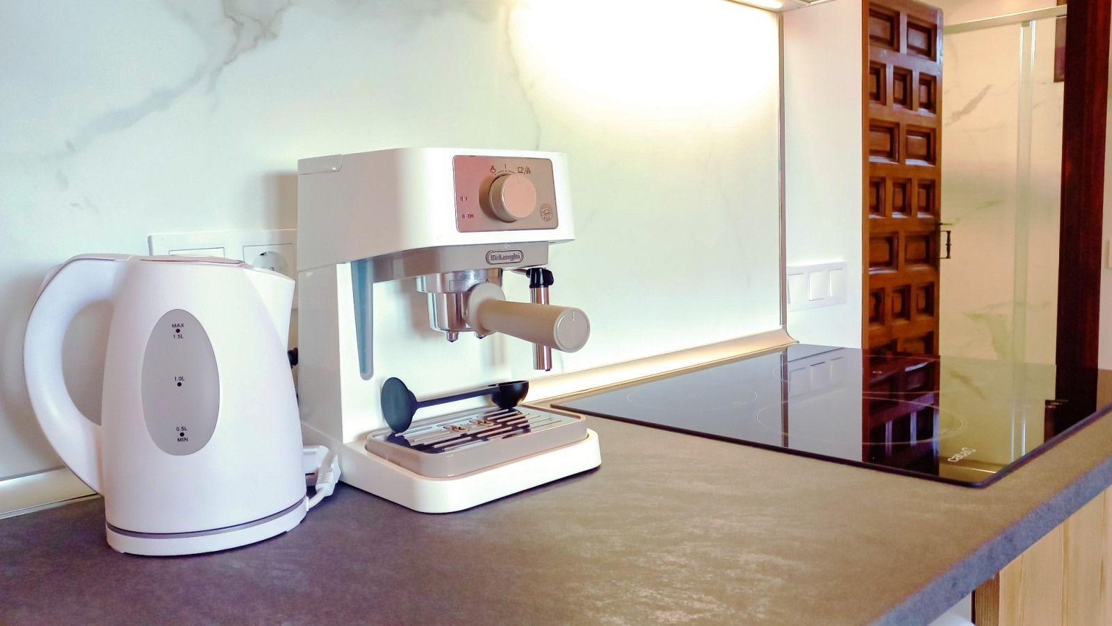 Hervidor eléctrico blanco y máquina de café expreso sobre un mostrador.