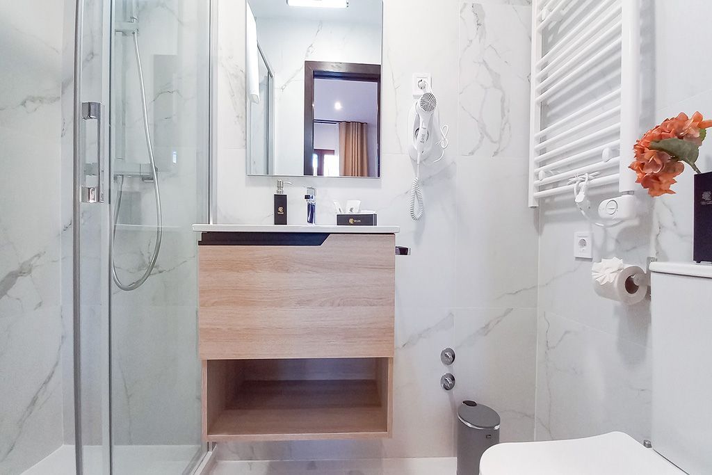 A bathroom with a toilet , sink , shower and mirror.