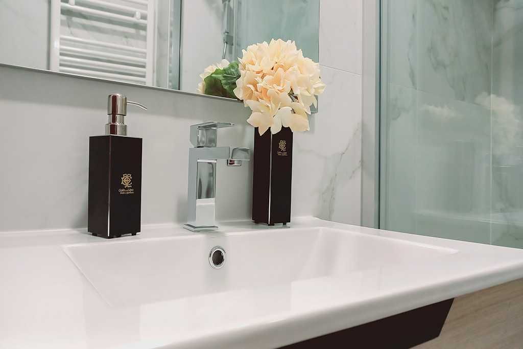 Lavabo de baño con dispensador de jabón y flores.
