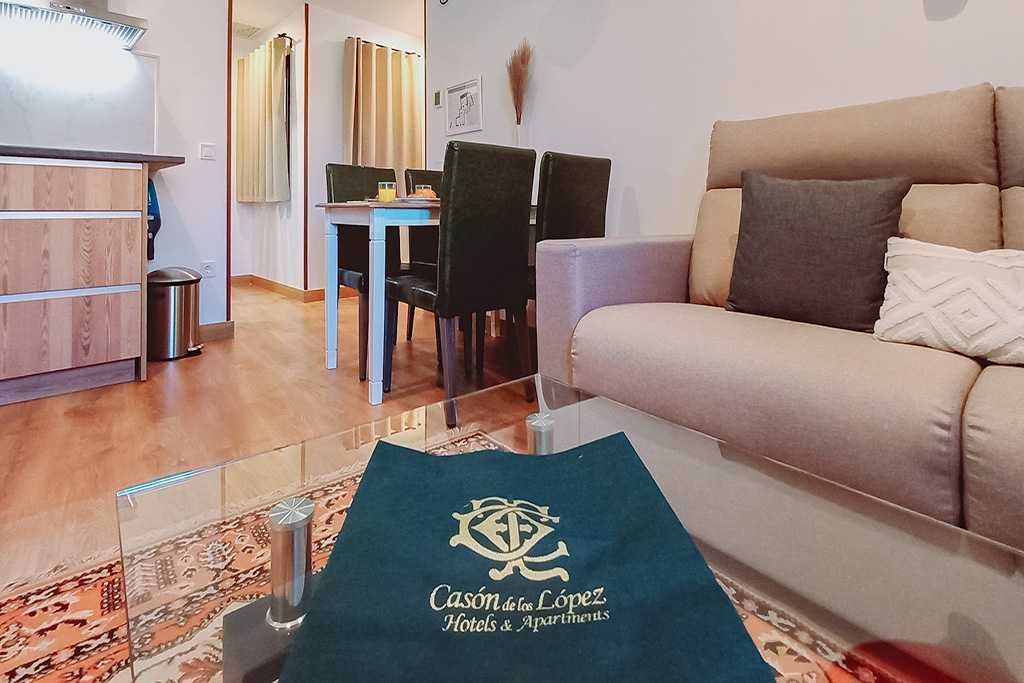 Sala de estar con sofá, mesa de comedor y un mantel verde con texto dorado.