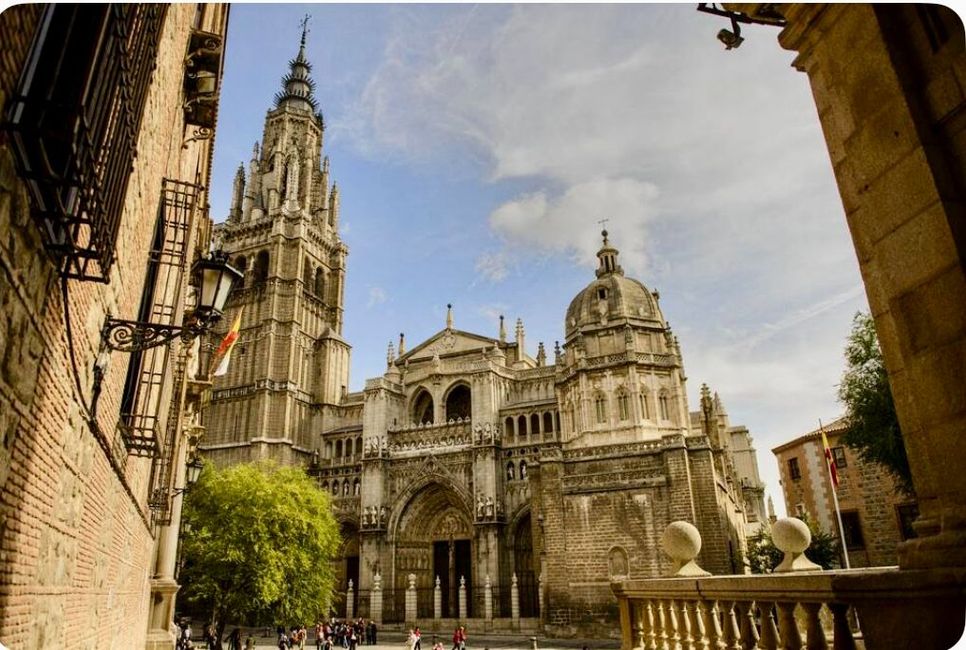 Catedral de Toledo, España. Arquitectura gótica con una alta aguja, fachada de piedra y cielo azul.