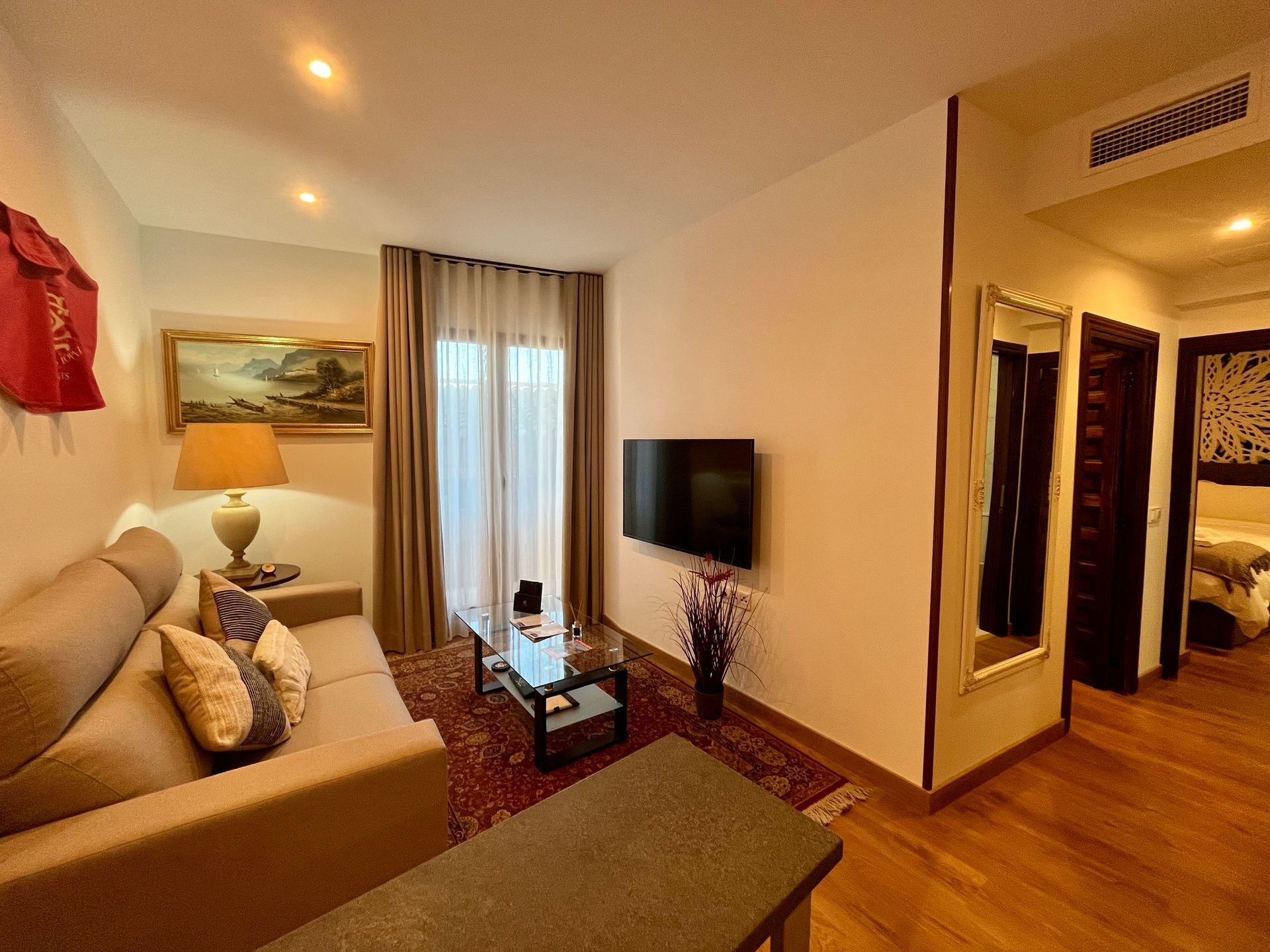 Acogedora sala de estar con sofá, TV, obras de arte y una vista de un dormitorio.