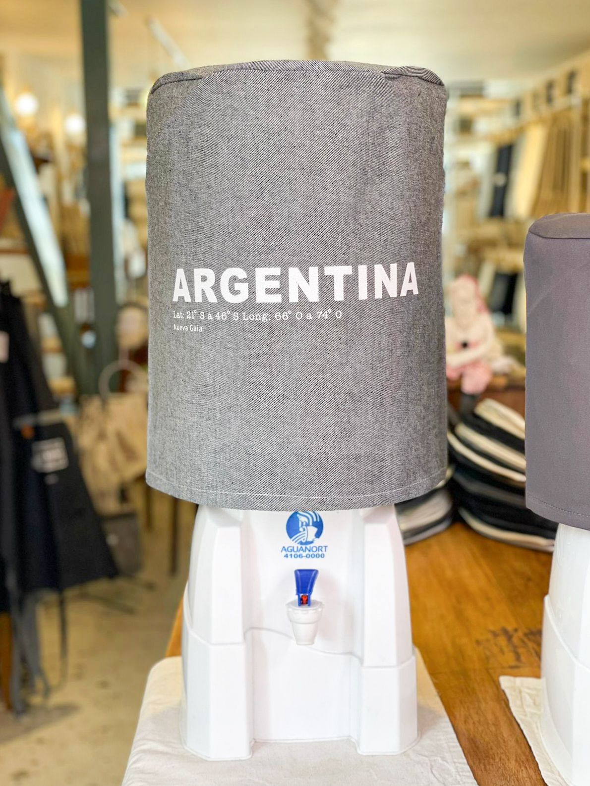 Dispensador de agua de marca argentina con tapa gris en un expositor de tienda, centrado en la imagen.
