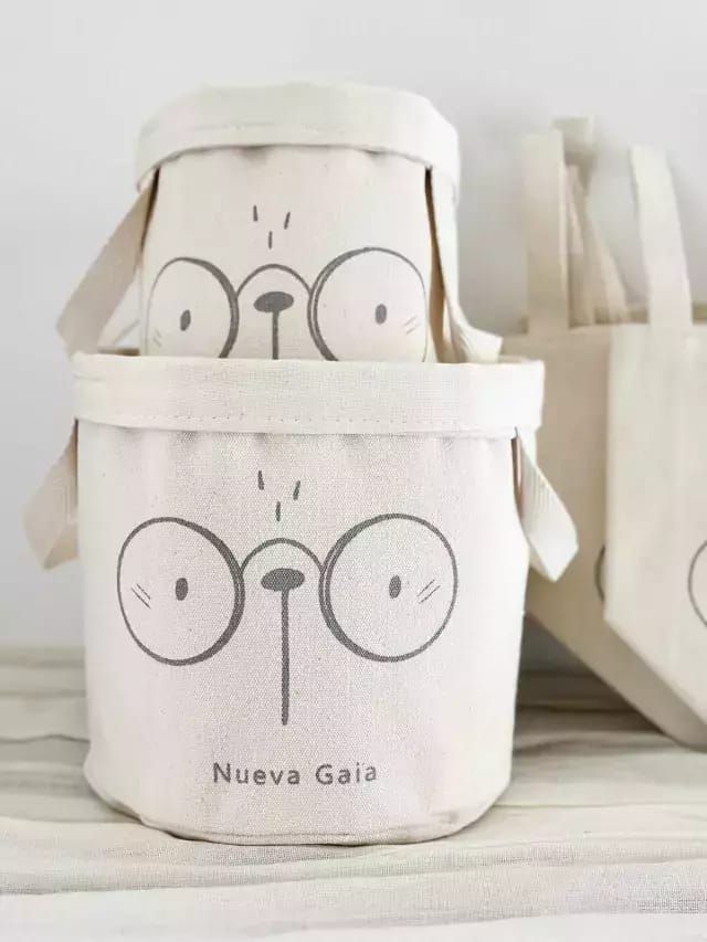 Bolso de lona blanco con la cara de un oso de dibujos animados y el texto “Nueva Gaia” impreso.
