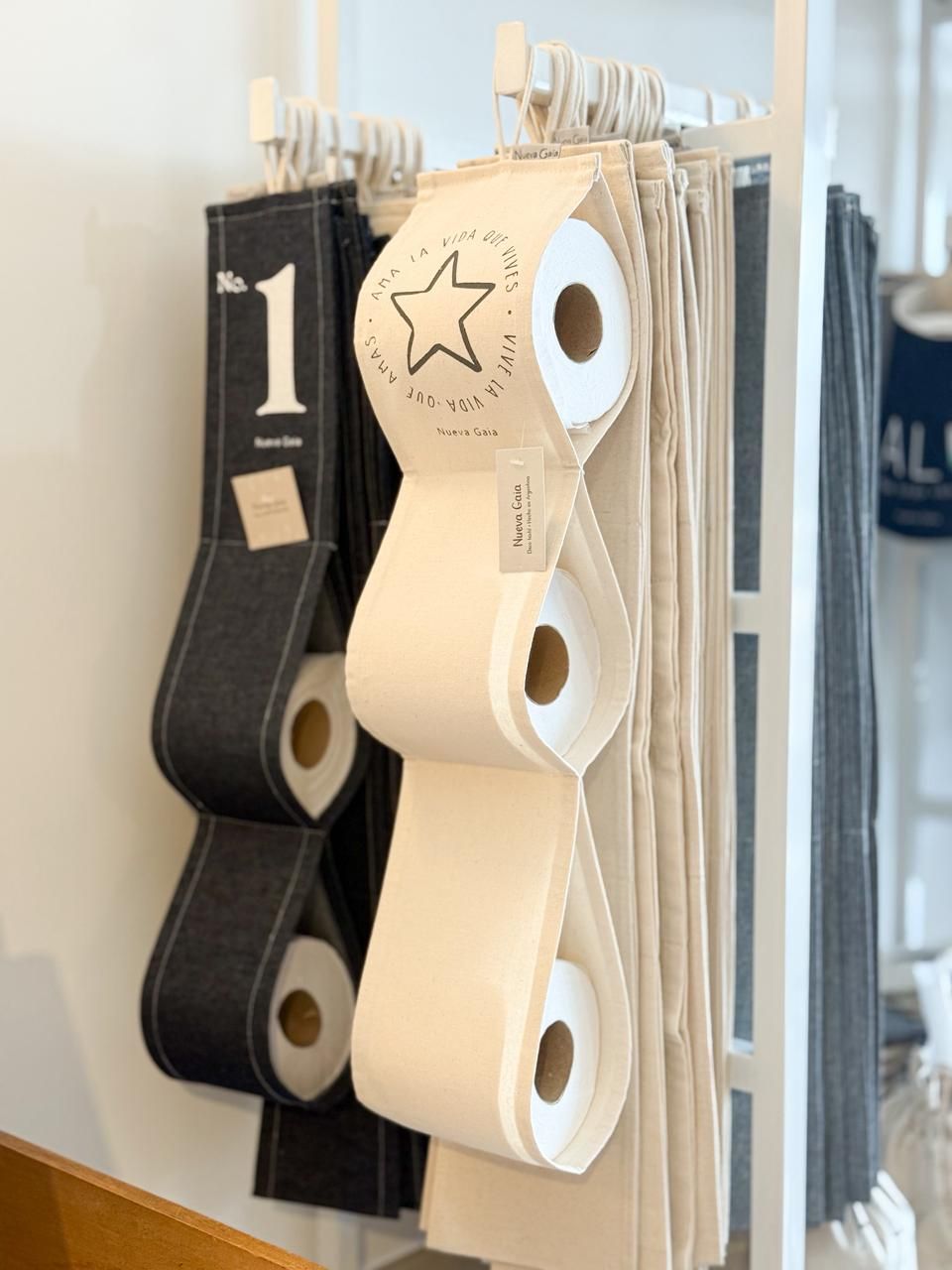 Rollos de cinta de tela negra, beige y blanca colgando de un organizador montado en la pared.
