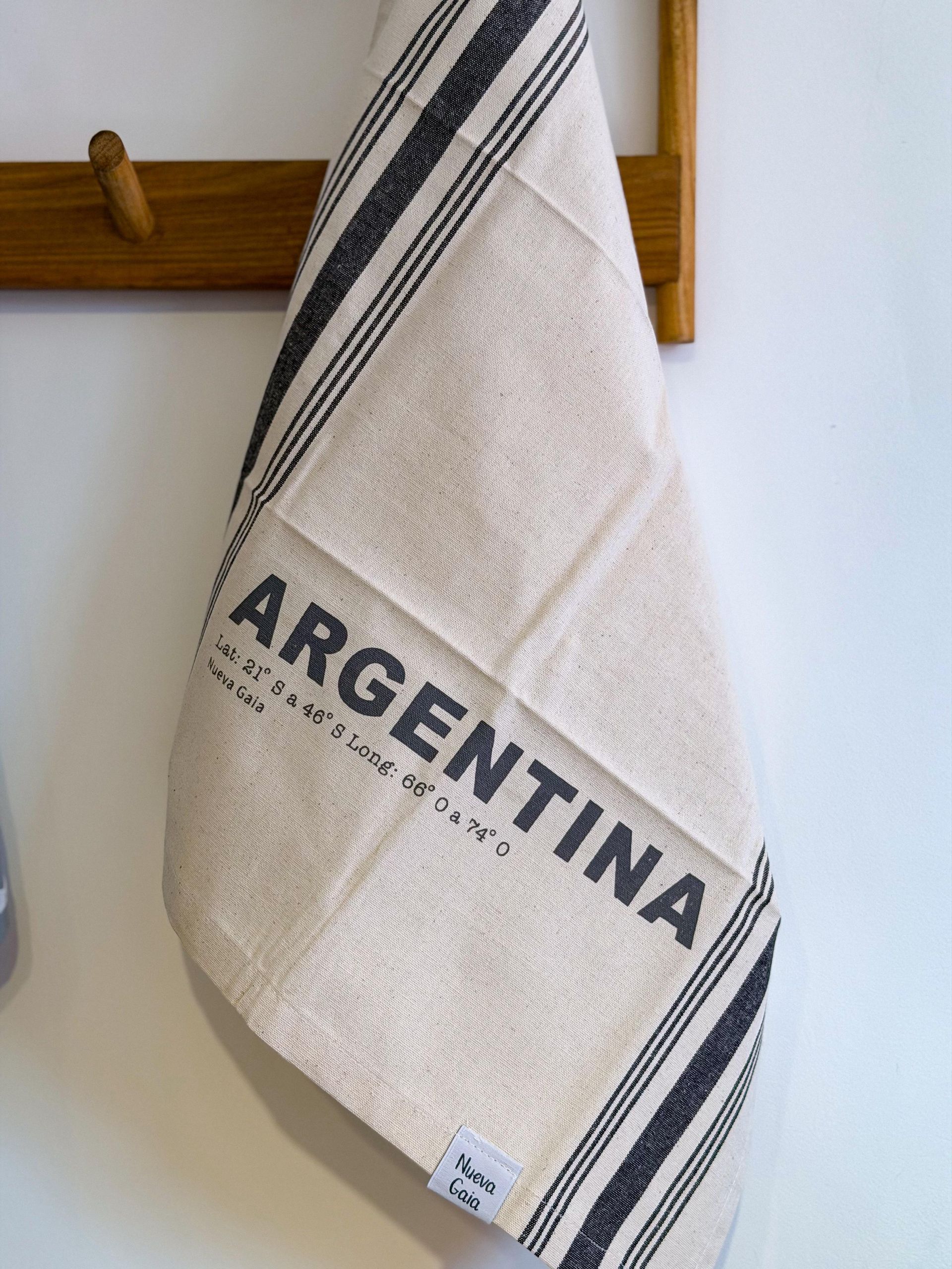 Estantería de madera tipo escalera que sostiene textiles doblados y revistas en una habitación de tonos neutros.
