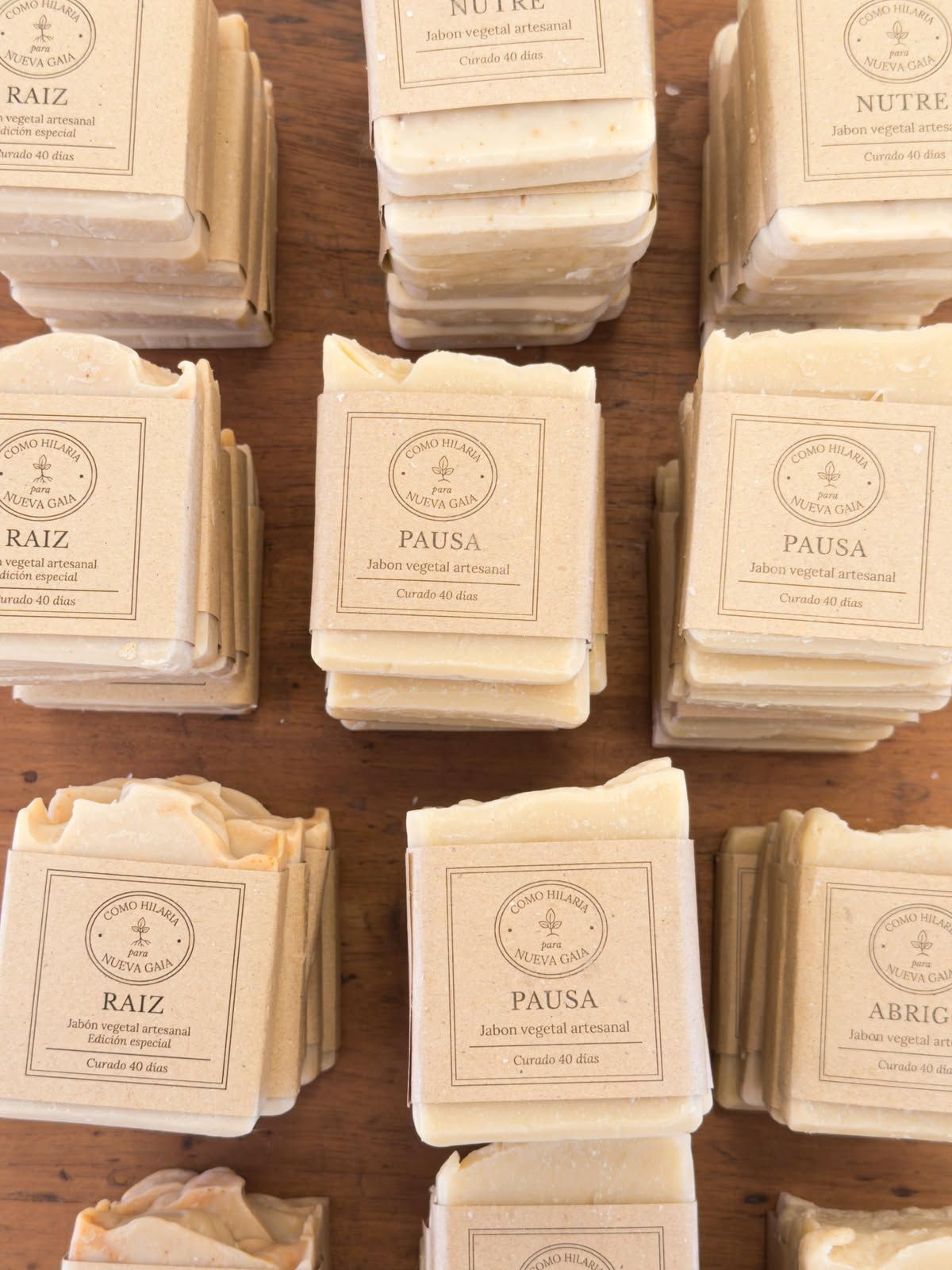 Montones de tarjetas dobladas de color crema con elegantes etiquetas dispuestas sobre una superficie de madera.