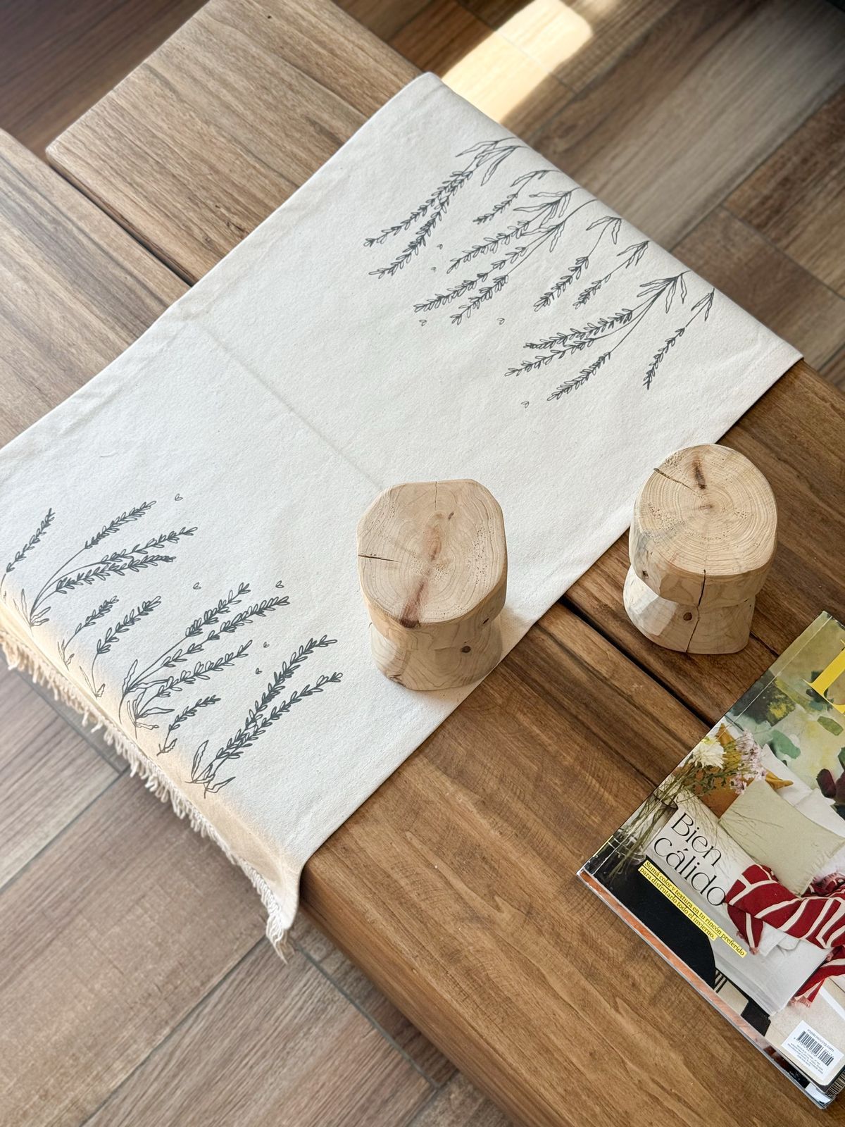 Camino de mesa blanco bordado con portavelas de madera sobre una mesa de centro en una sala de estar.