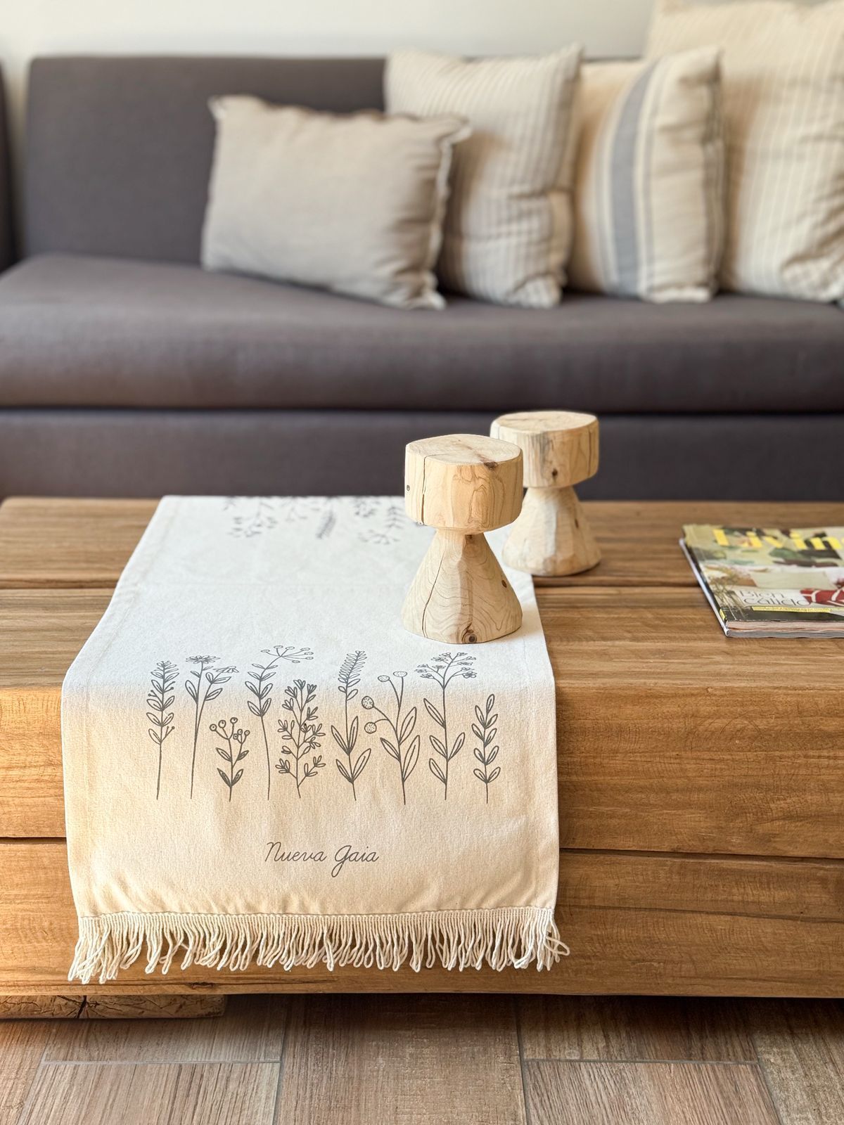 Camino de mesa blanco bordado con portavelas de madera sobre una mesa de centro en una sala de estar.