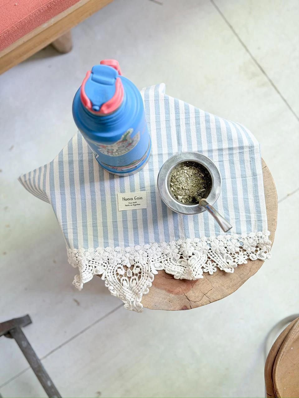 Bolsita de encaje a rayas azules y blancas sobre una rodaja de madera con una pequeña etiqueta.