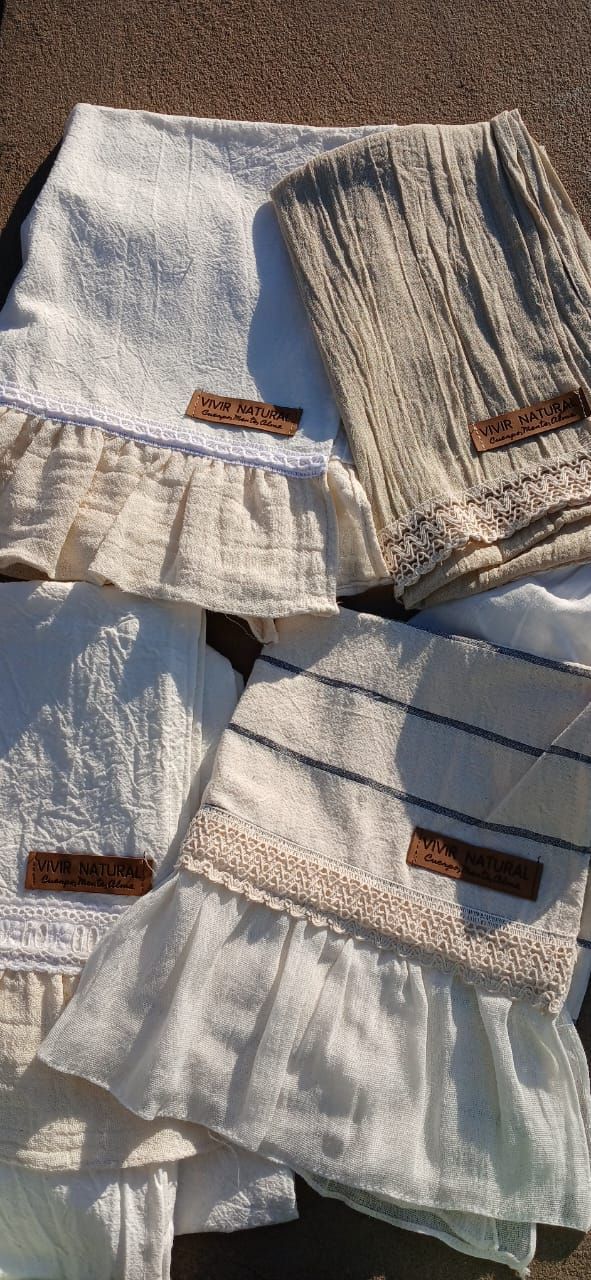 Pantalones y bermudas de tela blanca y beige con bolsillos, extendidos sobre un piso alfombrado.