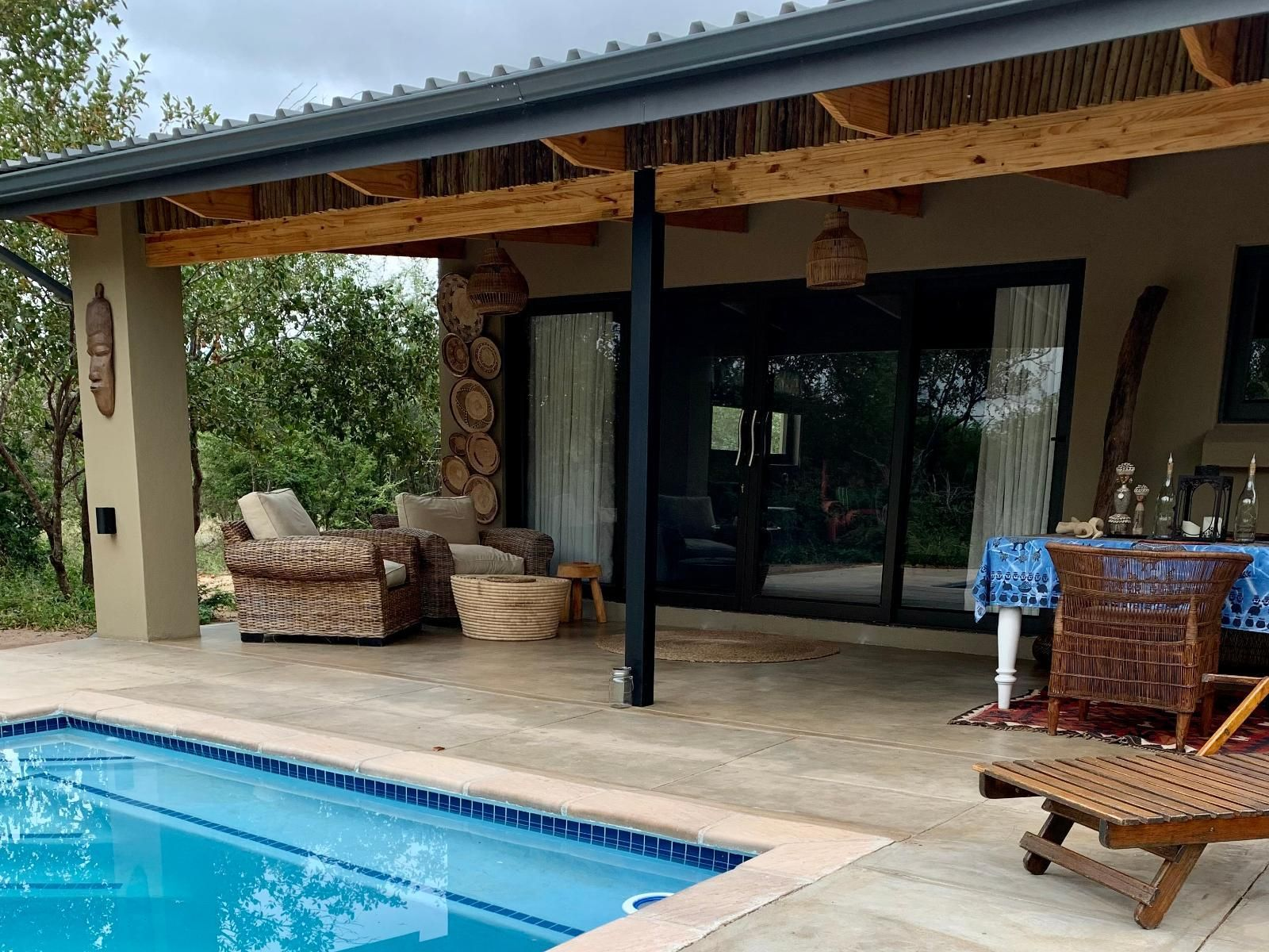 Poolside patio with seating, pool, and home.