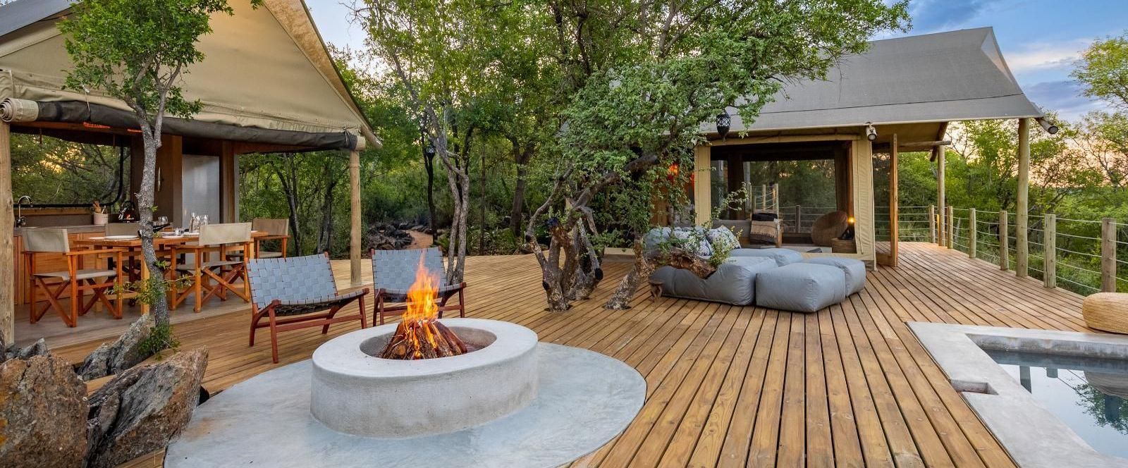 a wooden deck with a fire pit and a swimming pool in front of a tent