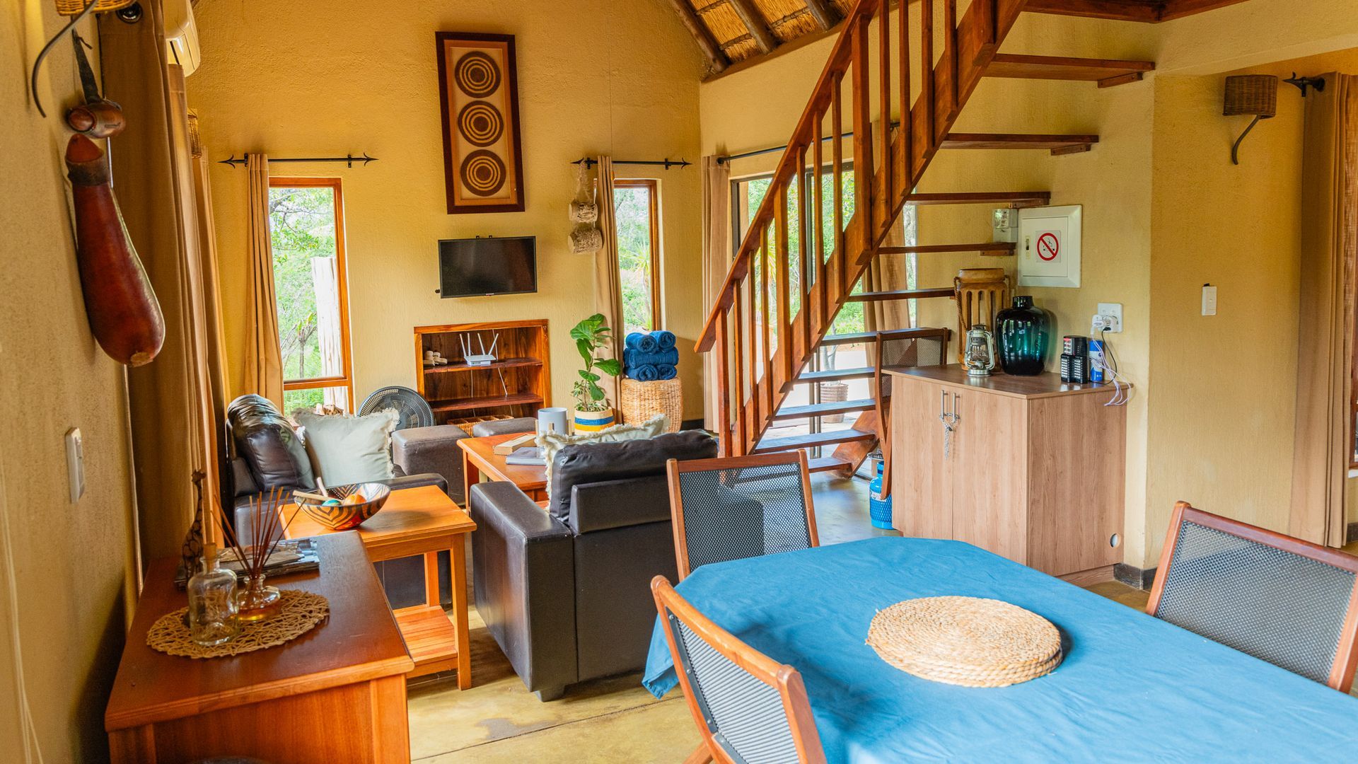 a living room with a table and chairs and stairs leading up to the second floor .