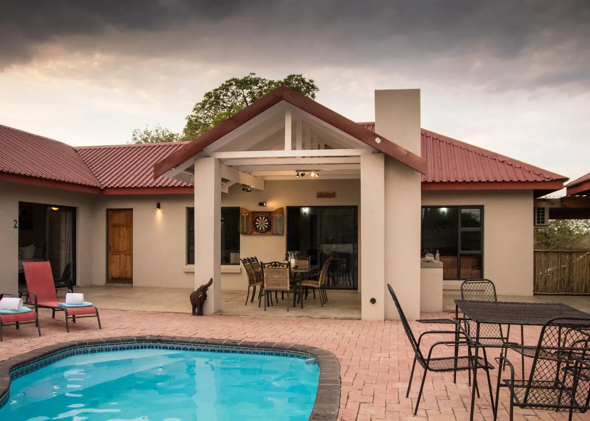 House with pool and patio furniture under an overcast sky.
