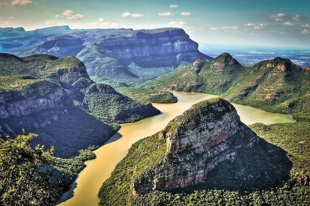Scenic aerial view of Blyde River Canyon, South Africa, with mountains, a lake, and lush green forests.