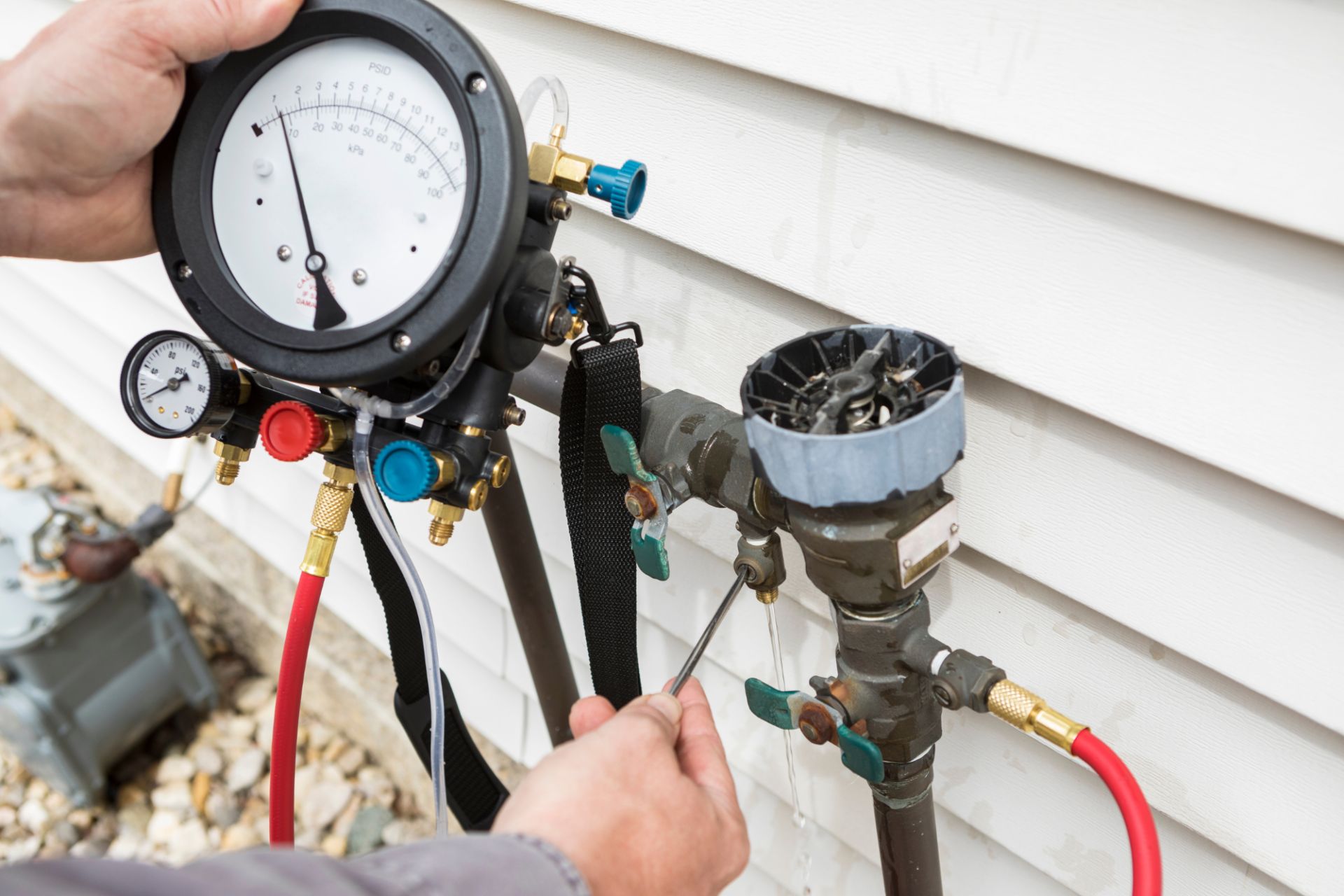 Technician using pressure gauges to service outdoor air conditioning lines