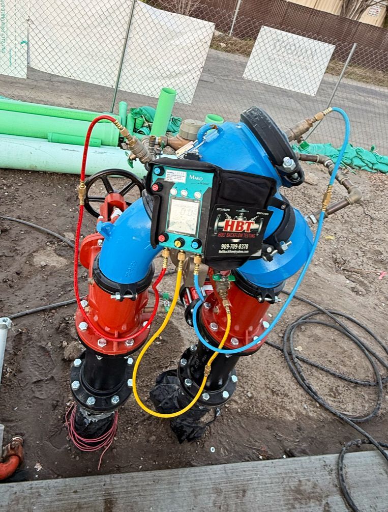 Blue and red industrial pipe assembly with gauges and hoses at a construction site