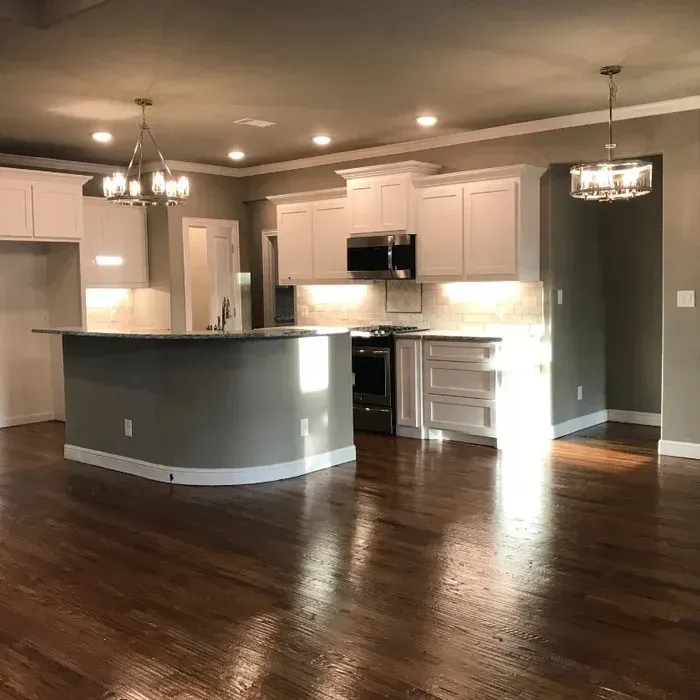 Spacious modern kitchen and dining area with white cabinets, dark wood floors, and pendant lights