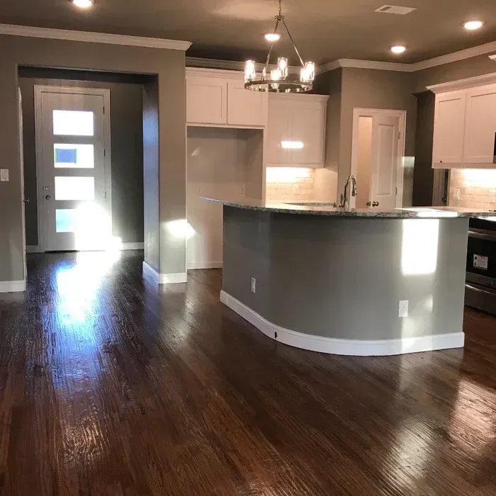 Open-plan kitchen with gray cabinets, dark hardwood floors, and a peninsula under pendant lights.