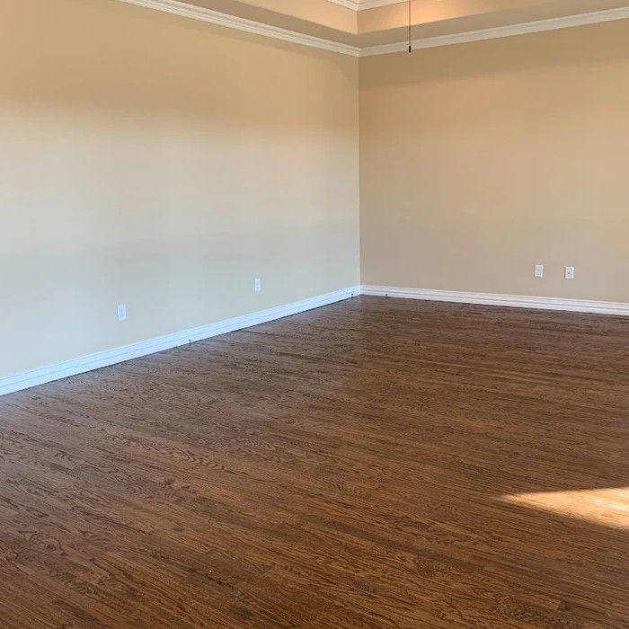 Empty beige room with hardwood floors and sunlight on the wall and floor