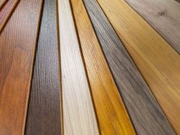 Assorted wood flooring planks in warm brown, gray, and gold tones arranged in a fan pattern