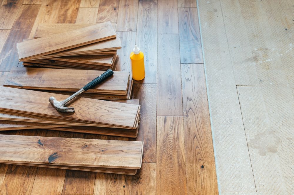 Stacked wood planks with a hammer and yellow glue bottle on a wooden floor