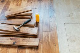 Stacked wood planks with a hammer and yellow glue bottle on a wooden floor