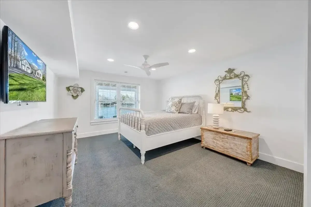 Bright white bedroom with a bed, dresser, mirror, wall TV, and sliding glass doors
