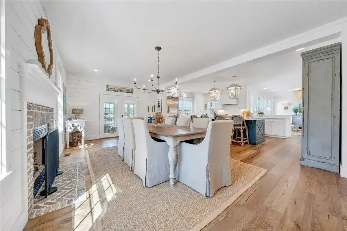 Bright open-concept kitchen and dining area with white cabinets, wood floors, and a central island