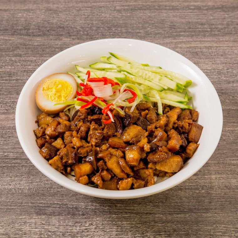 Bowl of braised pork rice with half-boiled egg, cucumber, and pickled vegetables on a wooden table
