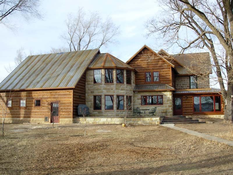Rustic wooden lodge with large windows and a metal roof in a leafless winter landscape