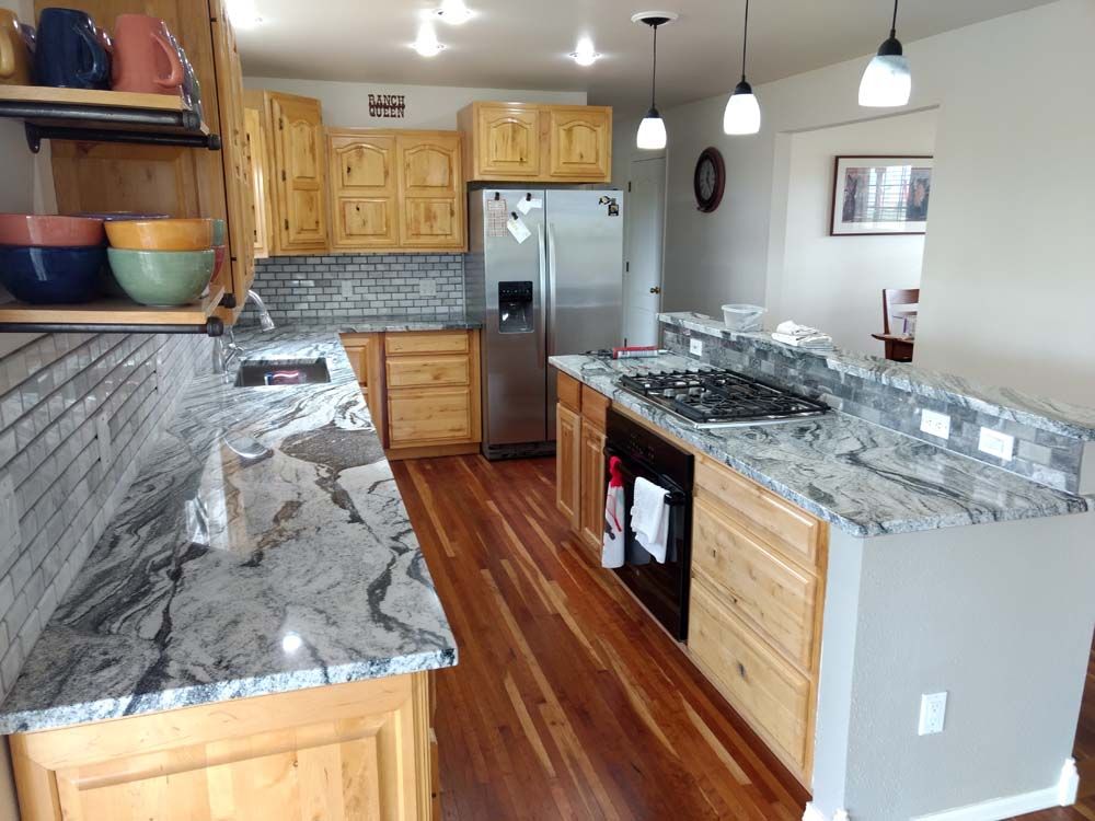 Modern kitchen with granite countertops, stainless steel fridge, wood cabinets, and hardwood floors