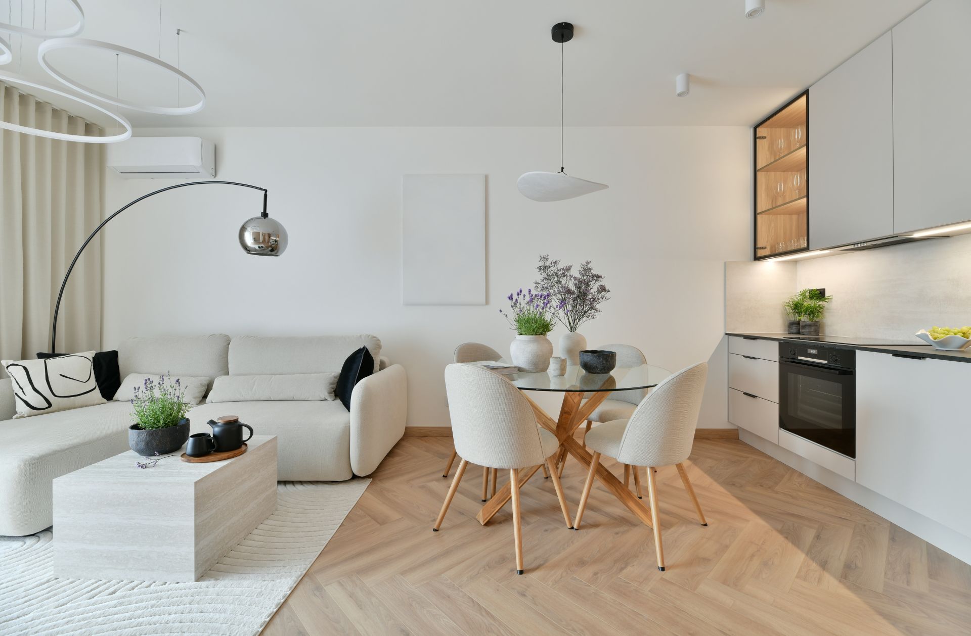 Bright modern living room with white sofa, dining table, and open kitchen in a minimalist apartment