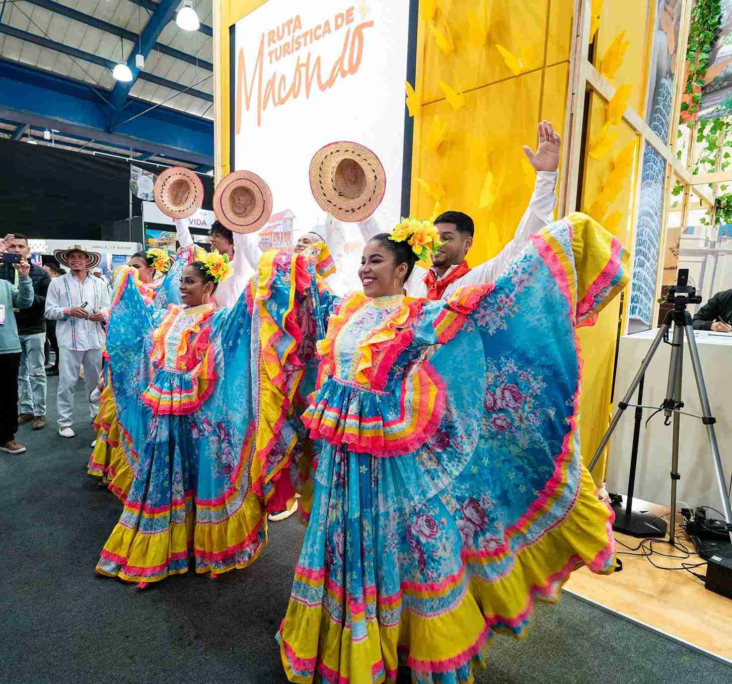Grupo folclórico con trajes típicos en feria turística, representación cultural de Colombia.