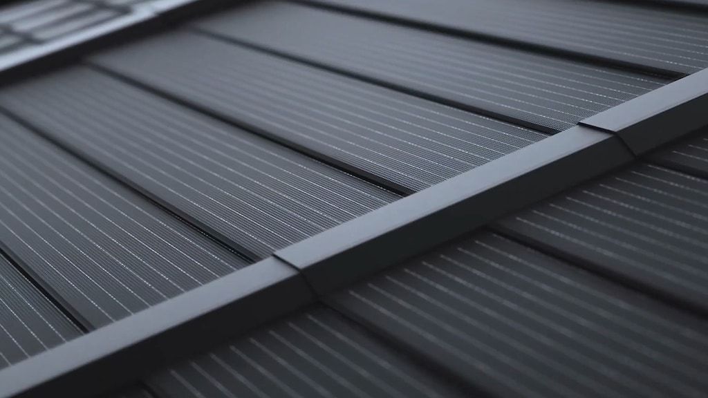 A close up of black nailable solar shingles attached to a roof