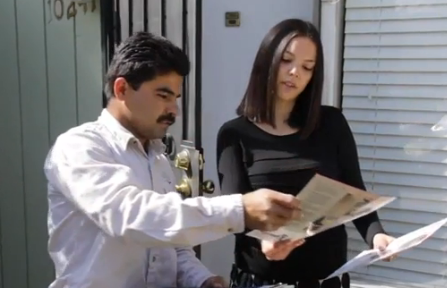 A man and a woman are looking at papers in front of a building with the number 04 on it